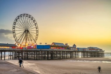 Günbatımında aydınlık iskele ve dönme dolaba sahip Blackpool sahilinin güzel manzarası. Birleşik Krallık