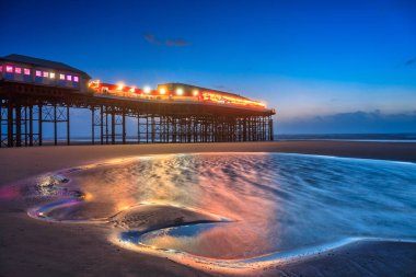 Beautiful landscape of Blackpool beach with illuminated pier at dusk. United Kingdom clipart