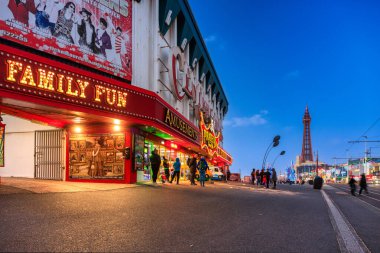 Blackpool, United Kingdom - October 20, 2024: People on Blackpool beach with tourist attractions and tower at dusk. clipart