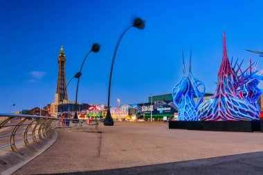 Blackpool, İngiltere - 20 Ekim 2024: Blackpool sahilinde turistik yerleri ve alacakaranlıkta kulesi olan insanlar.