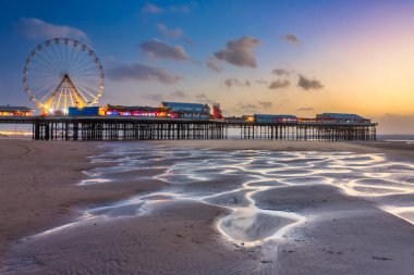 Günbatımında aydınlık iskele ve dönme dolaba sahip Blackpool sahilinin güzel manzarası. Birleşik Krallık