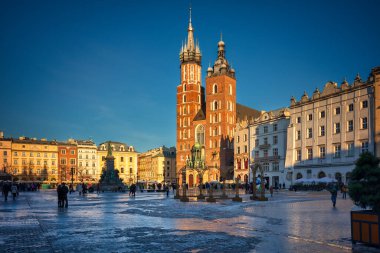 Krakow, Polonya - 17 Ocak 2025: Krakow 'daki Ana Pazar Meydanı batan güneşin ışığında. Polonya