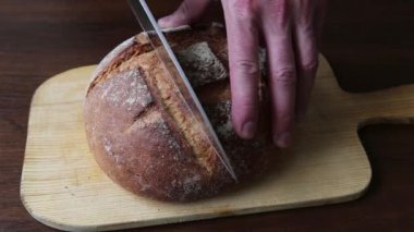 Slicing freshly baked bread on wooden table