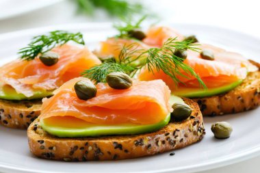 Taze dereotuyla süslenmiş tütsülenmiş somon kanapeleri ve kapariler avokado ile kızartılmış çoklu tahıllı ekmeğin üzerinde servis edilir. Yapay zeka üretken