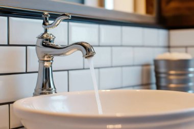 Şık bir musluktan seramik bir lavaboya akan ve modern banyo armatürlerini sergileyen tatlı su akıntısı. Yapay zeka üretken