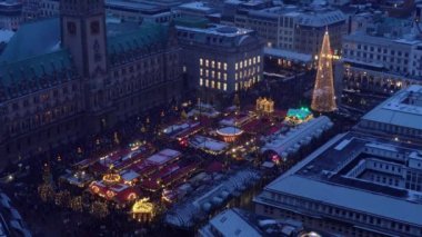 Akşamları Almanya 'nın Hamburg kentinde Rathausmarkt' taki aydınlatılmış tarihi Noel pazarının hava manzarası. Ren geyikli Noel Baba pazarda uçuyor..