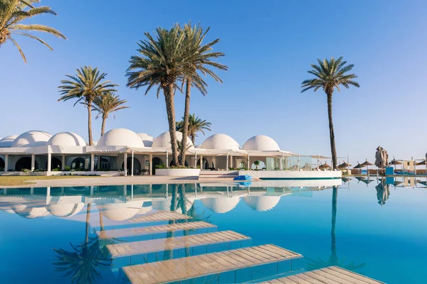 突尼斯 带有穹顶的传统建筑的游泳池和棕榈树 免版税图库图片
