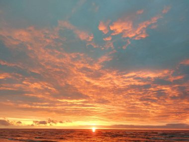 Beautiful sunset on the sea coast, the sun on a background of sky and clouds