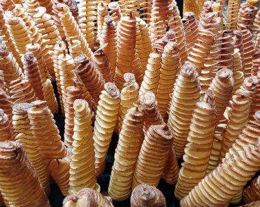 Lots of fried potatoes on sticks. Street food. Market. Snack.