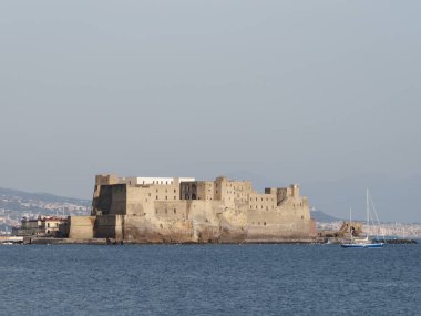 Napoli, İtalya. Castel Dell 'Ovo' nun önünde dalgakıran kayalar ve güzel bir günbatımı gökyüzü var..