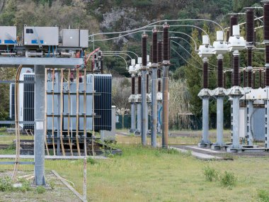 Elektrik dağıtım istasyonu. Bir sürü kablo, direk ve kalkan. Bahar, kara bulutların arka planında.