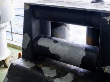 Kıç demirleme istasyonu üst yapının arkasındaki konteyner gemisinin kıç tarafında. Yeşil boyanmış ana güvertede beyaz ipler, siyah ve sarı kalın ipler ve yuvarlak uçlular var..