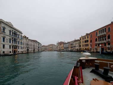 Venedik sokaklarında pencereleri olan yıpranmış binaların cepheleri gün ışığında kanal suyuna yakın.