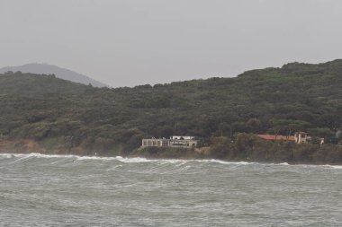 Dalgalar ve köpükler Toskana 'daki Baratti körfezinde kumsalda