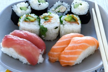 Plaka suşi rulo. Sushi, sashimi ve suşi rulo ahşap tabakta ayarlayın. Rulo ile Somon, yılan balığı, ton balığı, avokado, Kraliyet karides, krem peynir havyar tobica, chuka. Sushi menüsü. Japon yemekleri.