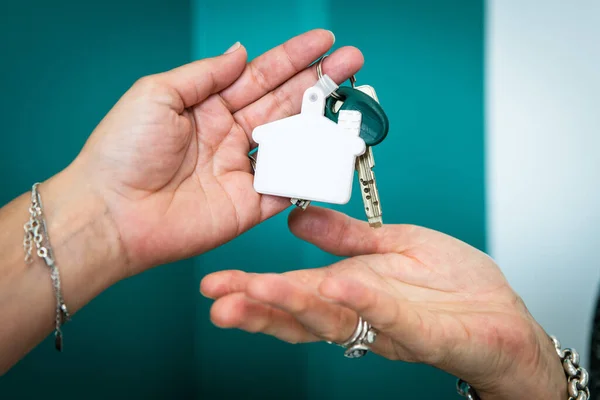 two hands are changing keys after house buying real estate