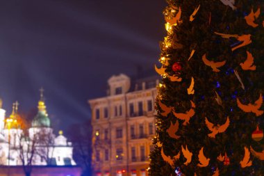 KYIV, UKRAINE - 24 Aralık 2022: Kyiv 'deki Sofiyivska Meydanı' ndaki Noel ağacı beyaz güvercinler ve Kyiv 'in savaşla ilgili zorluklarla ve sonuçlarla başa çıkmasına yardım eden ülkelerin bayraklarıyla süslendi