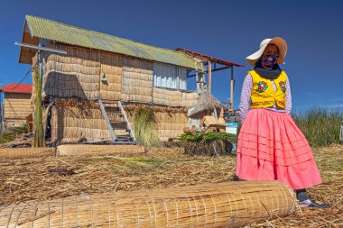 Uros, Peru - 29 Nisan 2022: Peru 'daki Titicaca Gölü' nde yüzen Uros Adaları 'ndaki ev yakınlarında geleneksel elbiseli kadınlar.