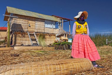 Uros, Peru - 29 Nisan 2022: Peru 'daki Titicaca Gölü' nde yüzen Uros Adaları 'ndaki ev yakınlarında geleneksel elbiseli kadınlar.