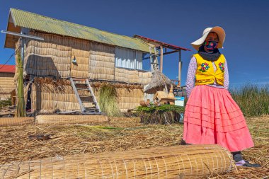 Uros, Peru - 29 Nisan 2022: Peru 'daki Titicaca Gölü' nde yüzen Uros Adaları 'ndaki ev yakınlarında geleneksel elbiseli kadınlar.