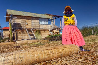 Uros, Peru - 29 Nisan 2022: Peru 'daki Titicaca Gölü' nde yüzen Uros Adaları 'ndaki ev yakınlarında geleneksel elbiseli kadınlar.