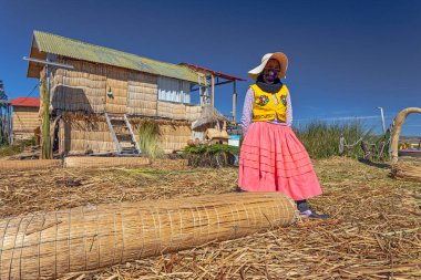 Uros, Peru - 29 Nisan 2022: Peru 'daki Titicaca Gölü' nde yüzen Uros Adaları 'ndaki ev yakınlarında geleneksel elbiseli kadınlar.
