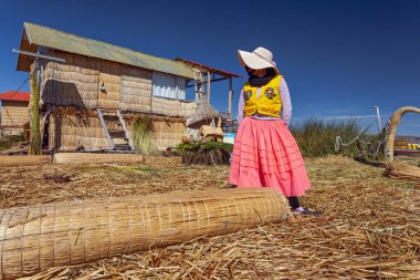 Uros, Peru - 29 Nisan 2022: Peru 'daki Titicaca Gölü' nde yüzen Uros Adaları 'ndaki ev yakınlarında geleneksel elbiseli kadınlar.