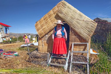 Uros, Peru - 29 Nisan 2022: Peru 'daki Titicaca Gölü' nde yüzen Uros Adaları 'ndaki ev yakınlarında geleneksel elbiseli kadınlar.