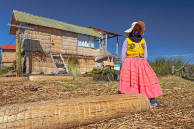 Uros, Peru - 29 Nisan 2022: Peru 'daki Titicaca Gölü' nde yüzen Uros Adaları 'ndaki ev yakınlarında geleneksel elbiseli kadınlar.
