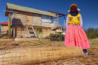 Uros, Peru - 29 Nisan 2022: Peru 'daki Titicaca Gölü' nde yüzen Uros Adaları 'ndaki ev yakınlarında geleneksel elbiseli kadınlar.