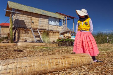 Uros, Peru - 29 Nisan 2022: Peru 'daki Titicaca Gölü' nde yüzen Uros Adaları 'ndaki ev yakınlarında geleneksel elbiseli kadınlar.