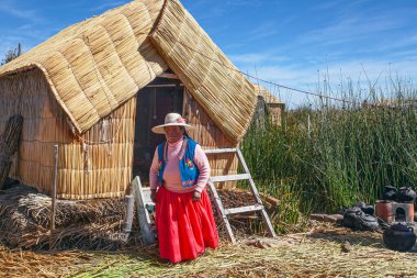 Uros, Peru - 29 Nisan 2022: Peru 'daki Titicaca Gölü' nde yüzen Uros Adaları 'ndaki ev yakınlarında geleneksel elbiseli kadınlar.