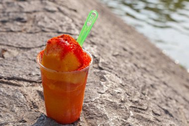 Sweet ice sorbet with mango taste with pepper chili powder and spices - Mexican traditional stret food