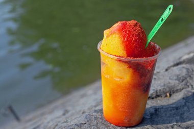 Sweet ice sorbet with mango taste with pepper chili powder and spices - Mexican traditional stret food