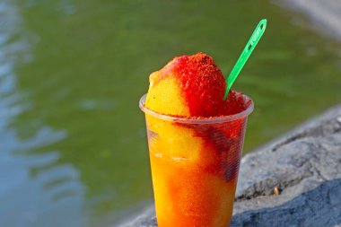 Sweet ice sorbet with mango taste with pepper chili powder and spices - Mexican traditional stret food