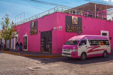 San Pedro Cholula, Mexico, March 18, 2022 - Beautiful Cholula street with  pink public bus, traditional  buildings and r shops with vibrant colored facades.