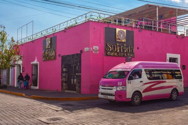 San Pedro Cholula, Mexico, March 18, 2022 - Beautiful Cholula street with  pink public bus, traditional  buildings and r shops with vibrant colored facades.