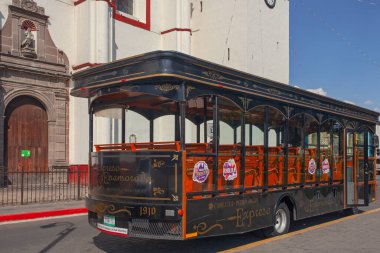 Cholula, Mexico - March 18, 2022 - The tourist sightseeing  bus parked beside Cathedral in Cholula, Puebla, Mexico.