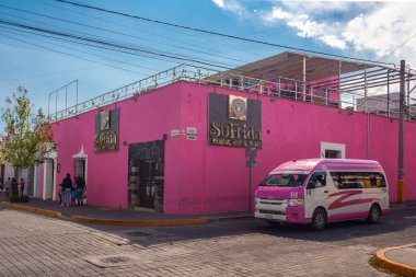 San Pedro Cholula, Mexico, March 18, 2022 - Beautiful Cholula street with  pink public bus, traditional  buildings and r shops with vibrant colored facades.