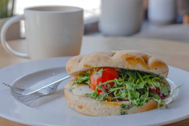 Beyaz tabakta Capsese ciabatta, tahta masada kahve.