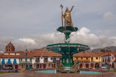 CUSCO, PERU - 30 Nisan 2022: Peru 'daki Cusco Plaza de Armas' daki su çeşmesinin üzerinde duran İnka İmparatoru Manco Capac 'a adanmış heykel. Sol tarafta İsa Cemiyeti Kilisesi duruyor..