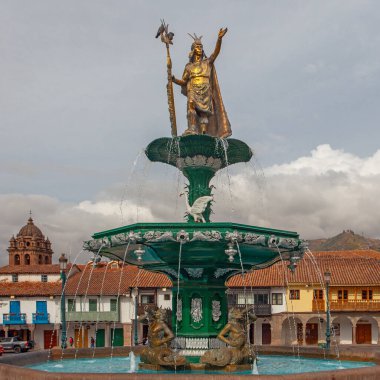 CUSCO, PERU - 30 Nisan 2022: Peru 'daki Cusco Plaza de Armas' daki su çeşmesinin üzerinde duran İnka İmparatoru Manco Capac 'a adanmış heykel. Sol tarafta İsa Cemiyeti Kilisesi duruyor..