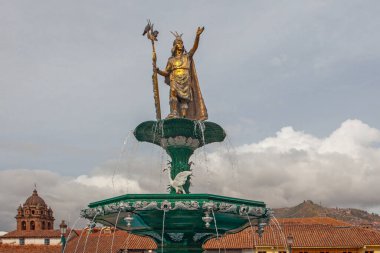 CUSCO, PERU - 30 Nisan 2022: Peru 'daki Cusco Plaza de Armas' daki su çeşmesinin üzerinde duran İnka İmparatoru Manco Capac 'a adanmış heykel. Sol tarafta İsa Cemiyeti Kilisesi duruyor..