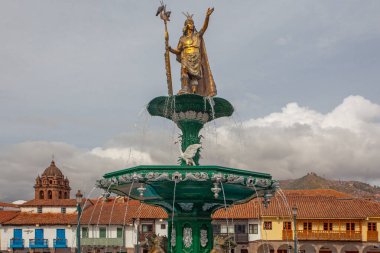 CUSCO, PERU - 30 Nisan 2022: Peru 'daki Cusco Plaza de Armas' daki su çeşmesinin üzerinde duran İnka İmparatoru Manco Capac 'a adanmış heykel. Sol tarafta İsa Cemiyeti Kilisesi duruyor..