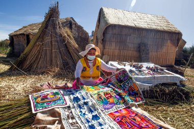 Uros, Peru - 29 Nisan 2022: Peru 'daki Titicaca Gölü' nde yüzen Uros Adaları 'ndaki ev yakınlarında geleneksel elbiseli kadınlar.