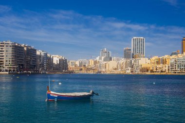 Malta - 9 Ferobot, 2024: Saint Julian Körfezi geleneksel renkli balıkçı tekneleri Luzzu, Malta