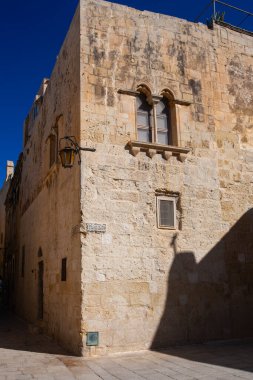 Mdina, Malta - 14 Şubat 2024: Mdina 'daki antik binalarda taş duvarlar, eski Malta' nın eski başkenti Mdina 'nın dar sokaklarında eski taş duvarlar ve gölgeler
