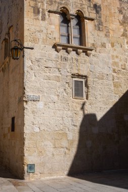 Mdina, Malta - 14 Şubat 2024: Mdina 'daki antik binalarda taş duvarlar, eski Malta' nın eski başkenti Mdina 'nın dar sokaklarında eski taş duvarlar ve gölgeler