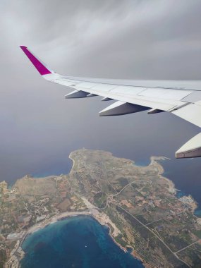 Clouds and a wing of Wizzair airbus from the airplane window. over Malta islands and Mediterranean sea clipart