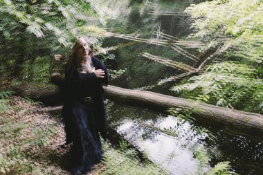 Gölün yanındaki ormanda siyah bir kadın. Bir cüce, birden fazla açıklama.